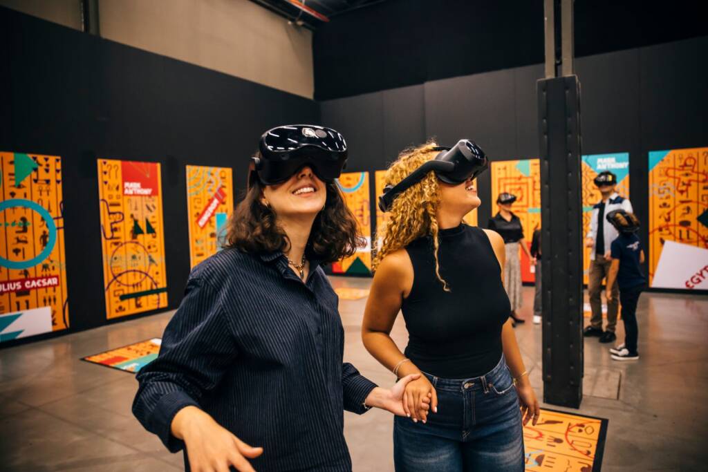 Dos mujeres andando por el metaverso de Cleopatra con el casco de realidad virtual